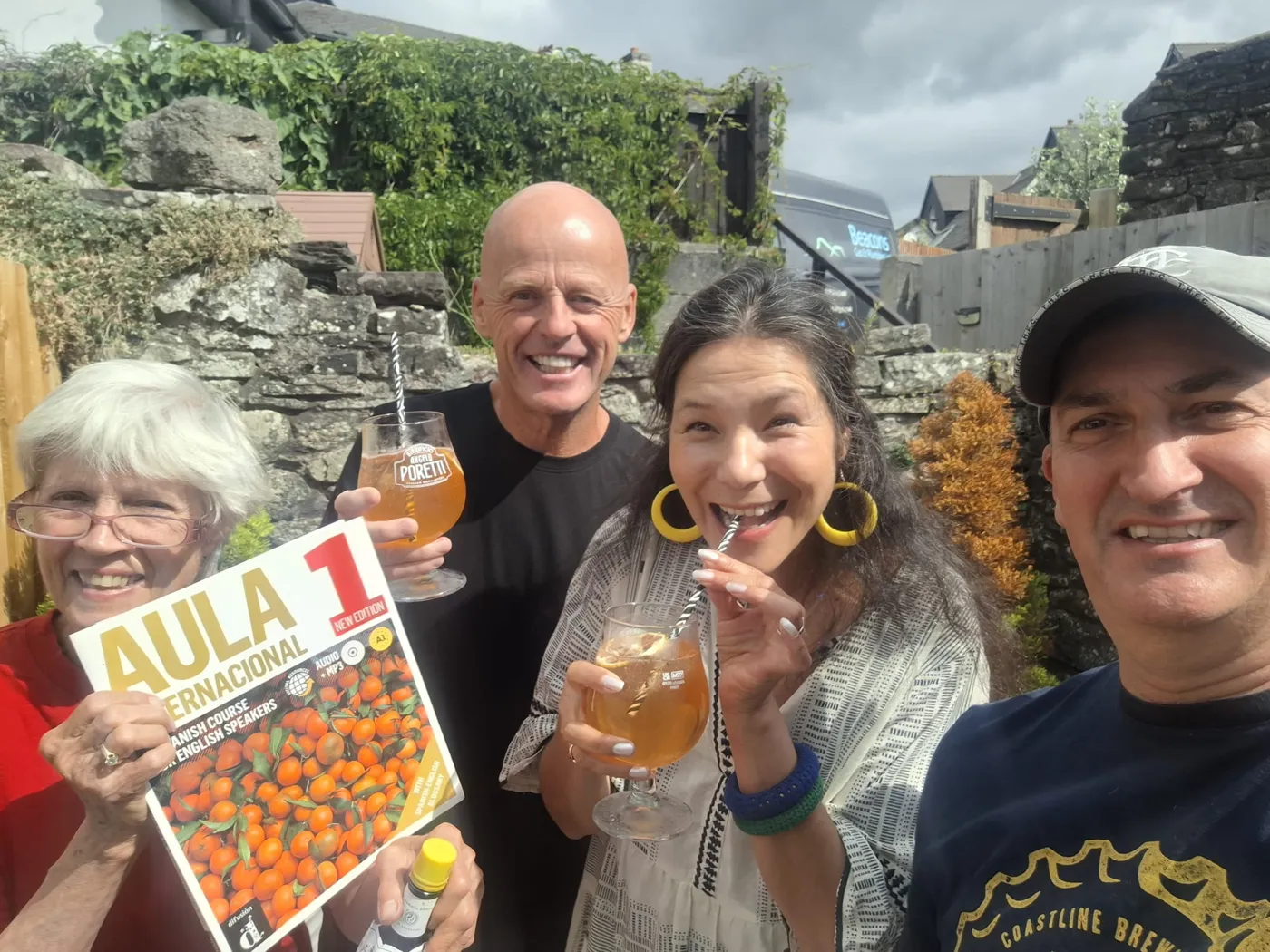 Smiling Spanish learners taking a group selfie with an Aula Spanish textbook