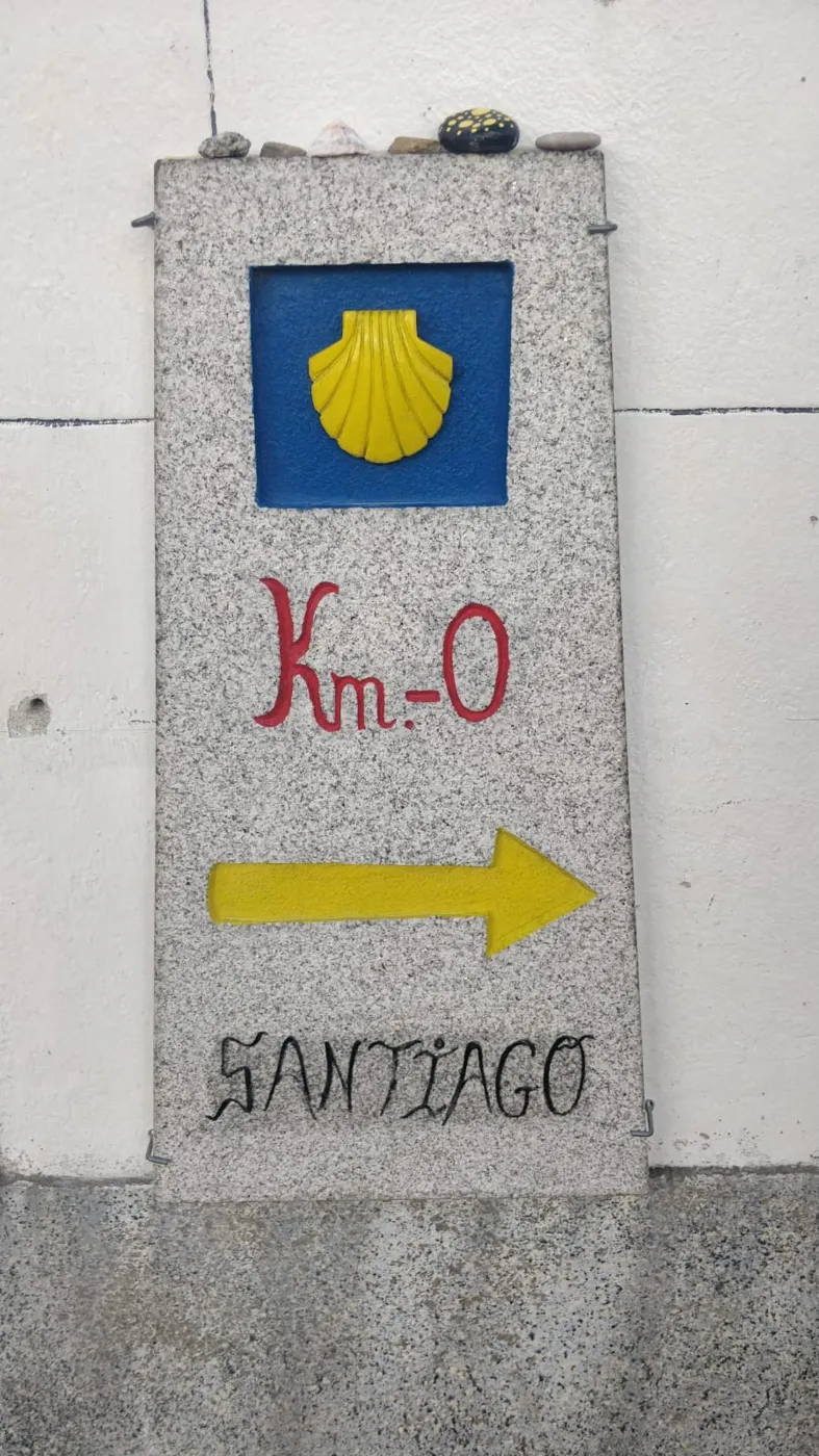 Camino stone marker with the yellow shell pointing to Santiago